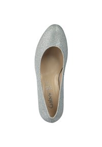 Scarpa con tacco alto glitterato argento, dalla punta rotonda e con fianchi aperti, dotata di una soletta beige. La superficie liscia esalta la sua lucentezza.