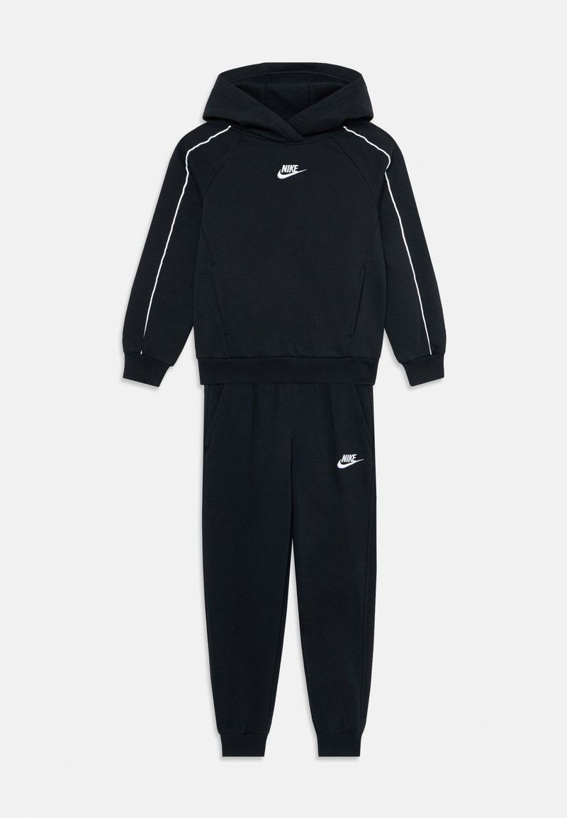 Ensemble hoodie et joggers noir Nike avec des piping blancs sur les manches et des logos sur la poitrine et la cuisse gauche.