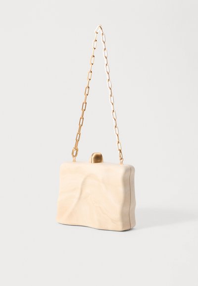 Sac à main en résine beige avec une texture ondulée, bandoulière en chaîne en métal doré et un fermoir arrondi sur le dessus. Forme rectangulaire simple.