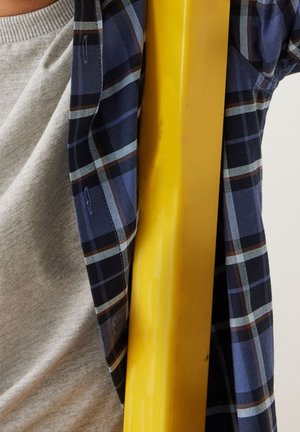 Yellow cylindrical object beside a gray fabric with a round neckline, covered partially by a blue plaid flannel with thin white and brown lines.