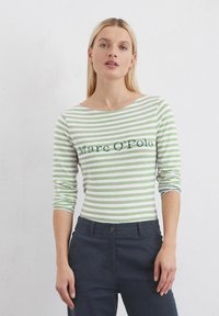 Maglietta a maniche lunghe a righe verdi e bianche con scollatura a barca, con il testo "Marc O'Polo" sul petto. Tessuto morbido e leggero.