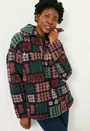 Fleece pullover jacket featuring a patchwork design in navy, green, burgundy, and cream with a zippered collar and soft texture.
