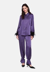 Purple satin two-piece set featuring an embellished shirt with feathered cuffs and matching trousers, designed with a loose fit and drawstring details.