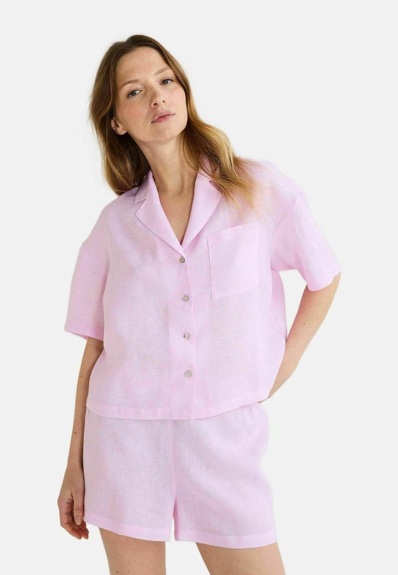 Chemise en lin rose clair à manches courtes avec une poche poitrine et cinq boutons, assortie à un short avec une taille élastique.