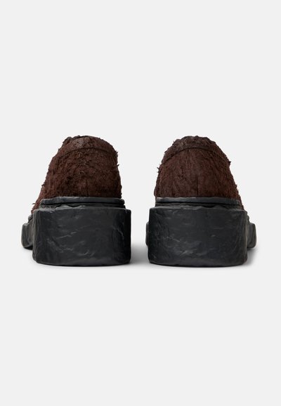 Bruna, texturerade slip-on skor med en kraftig svart platåsula, i rått, ostadigt material på ovandelen och släta kanter.