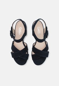 Černé semišové sandály s překříženými pásky, sponou na kotníku a polstrovanou stélkou. Plná podešev; navrženo pro pohodlí.