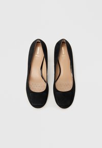 Mustat mokkakengät ballerina-mallissa, joissa on sileä pyöreä kärki, hillitty rei'itetty pohja ja kontrastinvärinen musta kumipohja. Brändilogo näkyy sisäpuolella.