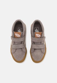 Sive besplatne tenisice s dva Velcro remena, gumeni potplat i perforirani detalji na prstima. Vans logotip na jeziku.