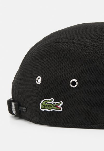 Casquette noire en tissu texturé avec un logo de crocodile brodé en vert et des trous de ventilation en argent. Sangle ajustable à l'arrière.
