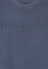 Sinine tekstuuriga kangast T-särk, millel on ümar kaelus ja keskel on reljeefne "HACKETT LONDON" logo.