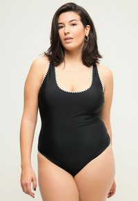 Černé jednocípuvé plavky s kulatým výstřihem, texturovaným bílým lemem podél okrajů a tenkými ramínky, vyrobené z hladkého materiálu.
