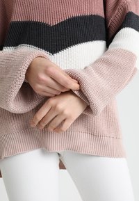 Gestrickter Pullover in Pink, Schwarz und Weiß mit vertikalen Streifen; verfügt über locker sitzende Ärmel und einen gerippten Saum. Weiche Textur und lässiges Design.