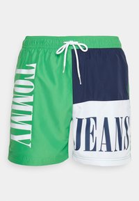 Shorts da bagno da uomo con un design a blocchi di colore verde, blu navy e bianco. Presentano la scritta "TOMMY" in grande lettering bianco e una vita con cordoncino.