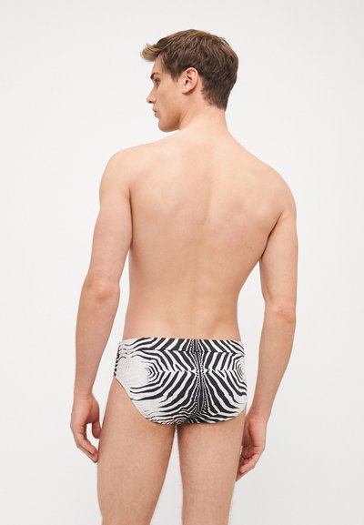 Costum de baie scurt cu dungi negre și albe, având un model geometric, cu un design cu talie joasă și o textură a materialului neted.