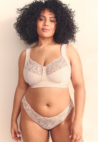 Set de lenjerie bej, format dintr-un sutien neted cu detalii din dantelă și bretele late, asortat cu chiloți cu margini de dantelă. Textură moale.