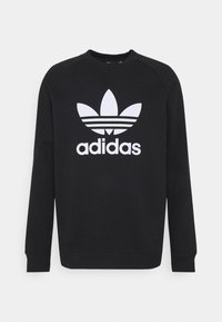 Svart sweatshirt i bomull med en stor vit Adidas-logotyp och tre horisontella ränder. Klassisk rund halsringning och långa ärmar.