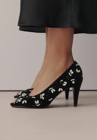 Pantofi cu toc înalt din suede negru, cu vârf deschis, împodobiți cu accente strălucitoare de cristal și motive florale pe laterale.