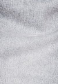 Primer plano de la textura de tela de mezclilla azul claro con un patrón de tejido visible y ligeras arrugas.