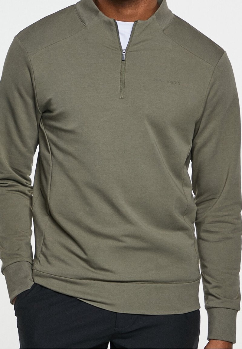 Sudadera de color verde oliva con cremallera de cuarto de vuelta, mangas largas y paneles texturizados en los hombros. Tela suave con detalles de logo sutiles.