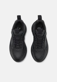 Schwarze Sportschuhe mit einem strukturierten Lederoberteil, das über ein Schnürdesign, eine gepolsterte Zunge und zwei Zuglaschen für einfaches Anziehen verfügt.