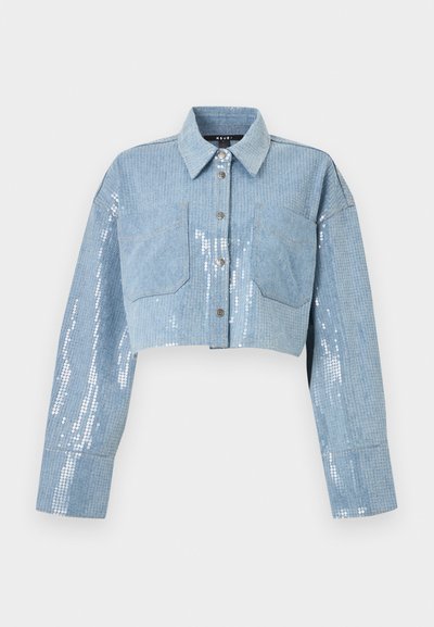 Φως μπλε κοντή τζιν ζακέτα με μακριά μανίκια, κούμπωμα με κουμπιά μπροστά, δύο τσέπες στο στήθος και λεπτομέρειες από ασημένιες παγιέτες πάνω στο ύφασμα.