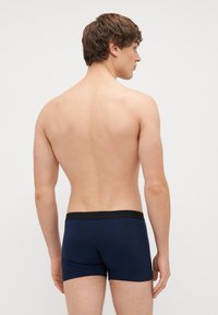 Dunkelblaue Boxershorts mit einem schwarzen elastischen Bund, enganliegendem Design und glatter Textur, von hinten gezeigt.