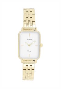 Montre rectangulaire dorée avec un cadran blanc, des index heures dorés et un bracelet en maillons métalliques. Marque "OOZOO" mise en avant.