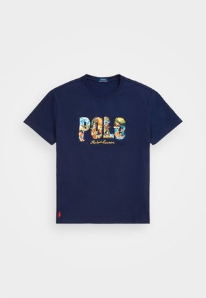 T-shirt en coton bleu marine avec un graphique "POLO" multicolore et des motifs tropicaux, et un petit logo rouge sur l'ourlet.