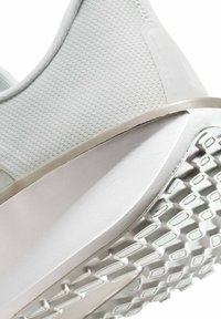 Talón de zapato deportivo blanco con parte superior de malla texturizada, entresuela gruesa acolchada y suela de goma con patrón para tracción.