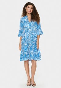 Robe bleue avec un motif floral, mi-longue, décolleté en V et manches cloche trois-quarts. Le tissu semble léger et fluide.