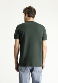 Groene katoen t-shirt met een ronde hals en korte mouwen, met een gladde textuur. Gepaard met lichtblauwe denim jeans.