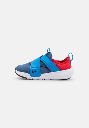 Barnesneaker i blå og rød med justerbare blå stropper, hvid sål, sort Nike-logo og trækkestropper på tungen og hælen.