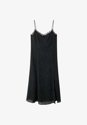 Robe nuisette noire à pois blancs, fines bretelles, bordure en dentelle au niveau de l'encolure et ourlet évasé, présentée sur fond blanc.