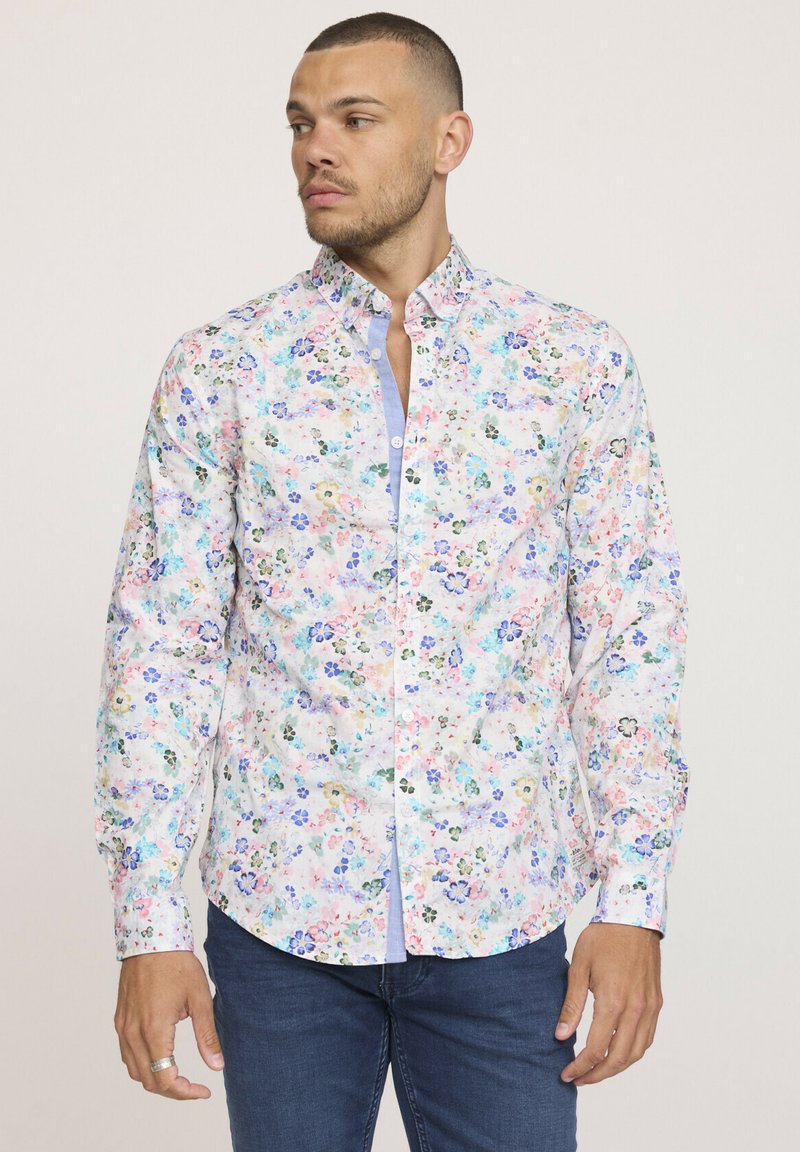 Chemise blanche à boutons avec un motif floral multicolore. Dotée de manches longues et d'une accent bleu sur le col. Le tissu semble lisse.