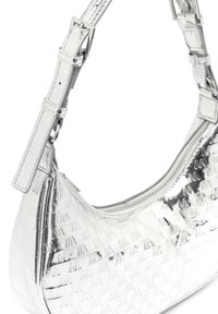Strieborná ramenná taška s embosovaným logom, so zakriveným tvarom, zapínaním na zips a nastaviteľným popruhom s prackou.