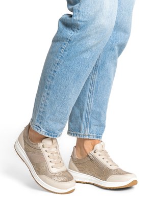 Beige teksturerede sneakers med snørebånd og sidelås, båret med lyseblå denimjeans, vist fra midt på læggen og ned på hvid baggrund.