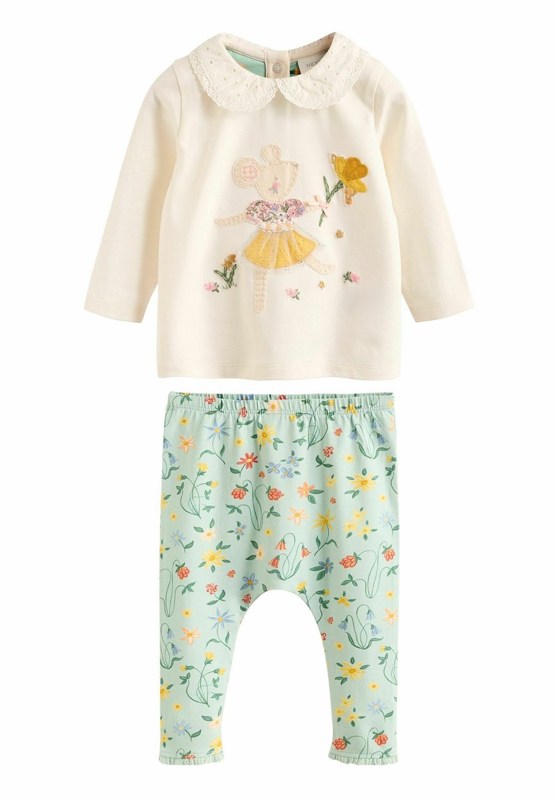 Zweiteiliges Outfit mit einem cremefarbenen Langarmtop mit Spitze am Kragen und Tierstickerei, kombiniert mit elastischen, grünen Blumenhosen.