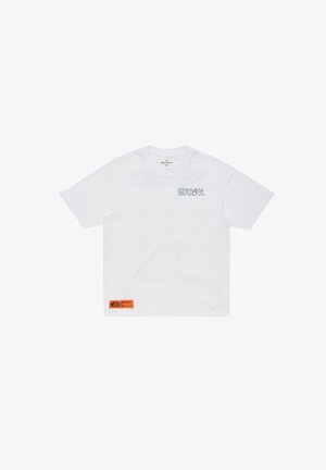 T-shirt bianca a maniche corte con la scritta "MUSXL" sul lato sinistro del petto e un'etichetta rettangolare arancione vicino all'orlo inferiore sul davanti.