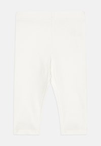 Leggings blancs à côtes fabriqués en tissu doux, avec une taille élastique et une coupe ajustée pour le confort et la liberté de mouvement.