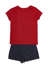 Camiseta de algodón roja con mangas cortas combinada con pantalones cortos de algodón azul marino que cuentan con una cintura elástica y un detalle de nudo en el dobladillo.