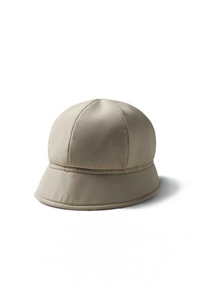 Beżowy wyściełany kapelusz typu bucket z przeszywanym wzorem paneli i lekko rozszerzaną krawędzią, przedstawiony na białym tle.