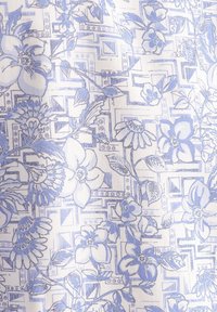 Tessuto floreale con motivi azzurri e bianchi, caratterizzato da fiori dettagliati e accenti geometrici su uno sfondo liscio e texturizzato.