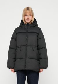 Black puffer jacket with a hood, featuring a front zipper, elastic drawstrings, and a quilted design with a matte finish.