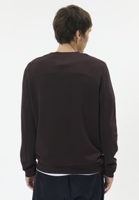 Dark brown sweatshirt with a crew neck, ribbed cuffs, and a seamless back design, made from soft fabric with a smooth texture.