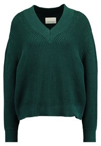 Zielony sweter z dzianiny o prążkowanej fakturze, szerokim dekolcie w kształcie litery V i luźnym kroju. Posiada długie rękawy i lekko skrócony dół. Brak ozdób.