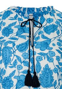 White fabric with blue floral print featuring black braided ties ending in black tassels at a gathered neckline.