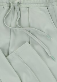 Lichtgroene sportbroek van glad, lichtgewicht stof. Voorzien van een elastische tailleband met trekkoorden en zijzakken.