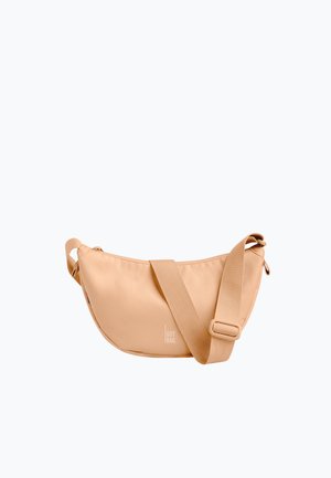 Beżowa torebka na ramię w kształcie półksiężyca z regulowanym szerokim paskiem i małym białym logo "GOT BAG." na środku z przodu.