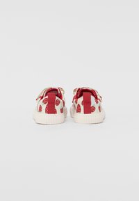 Rote und weiße Sneaker mit Erdbeer-Muster, Obermaterial aus Stoff, kontrastierende rote Fersenlasche und weiße Gummisohle. Lässiges Design.