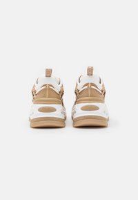 Sneakers Buffalo beige e bianchi visti da dietro, con suole spesse e talloni e linguette con marchio.